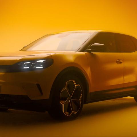 Full exterior view of the Ford Capri EV positioned on a yellow background, showcasing the vehicle’s silhouette and lighting design.