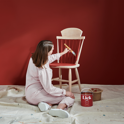Close-up of Lick paint tin and Heinz Tomato Ketchup bottle placed on a white table against red walls.