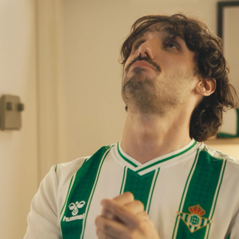 Close-up of a Real Betis fan wearing the club jersey, showing an emotional expression while looking upward.