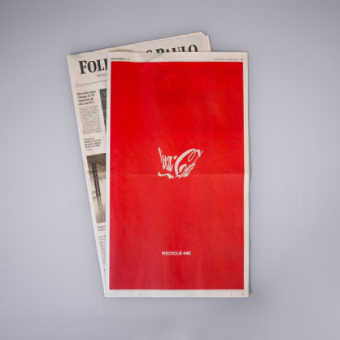 Coca-Cola Recycle Me print ad shown on a folded newspaper with a red cover and white Coca-Cola logo.