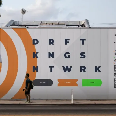 DraftKings Network outdoor mural featuring bold orange and green graphics with athletes in motion and interactive watch, listen, and play prompts.
