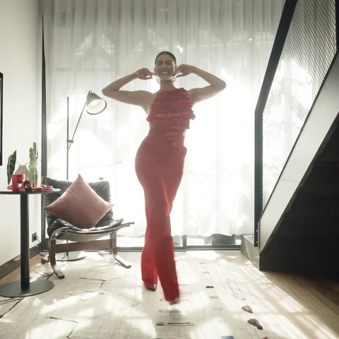 Woman in red styling poses with a magazine in a studio beauty portrait, showcasing a bright, confident smile for the Colgate Optic White campaign.