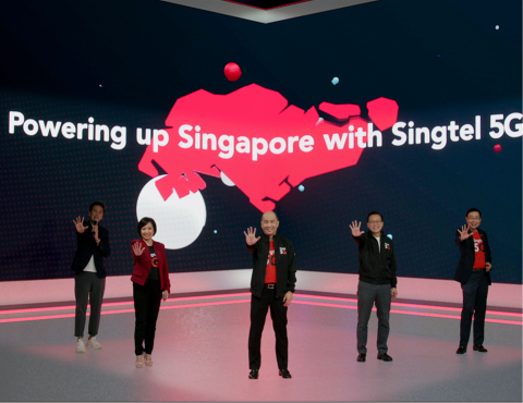 Group of Singtel representatives standing on a stage with a large screen behind them displaying “Powering up Singapore with Singtel 5G”.